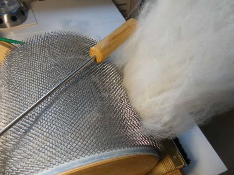 schöne weiche und weiße Wolle vom Patenschaf verlässt die Kardiermaschine